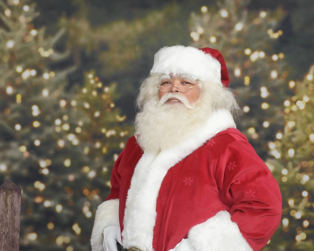 Camano Santa Joe Brigham portrait in front of lit Christmas trees