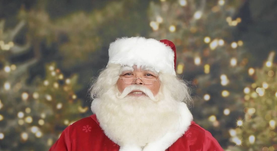 Camano Santa Joe Brigham in a red velvet Santa suit with snowflake belt buckle